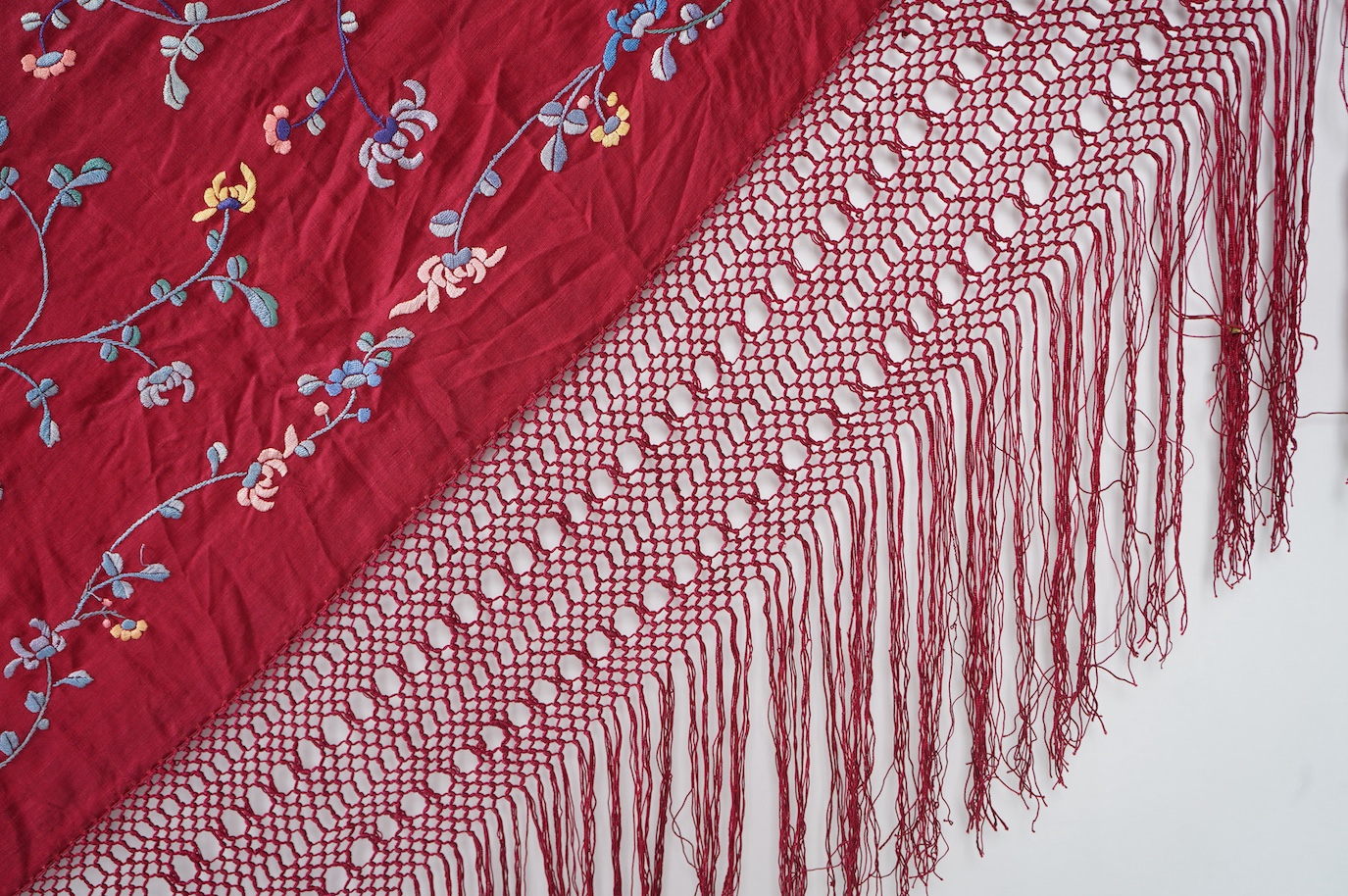 A late 19th early 20th century Chinese silk polychrome embroidered shawl on a maroon silk background. Fringed. 180cm x 60cm. Condition - no fading to colours, silk good